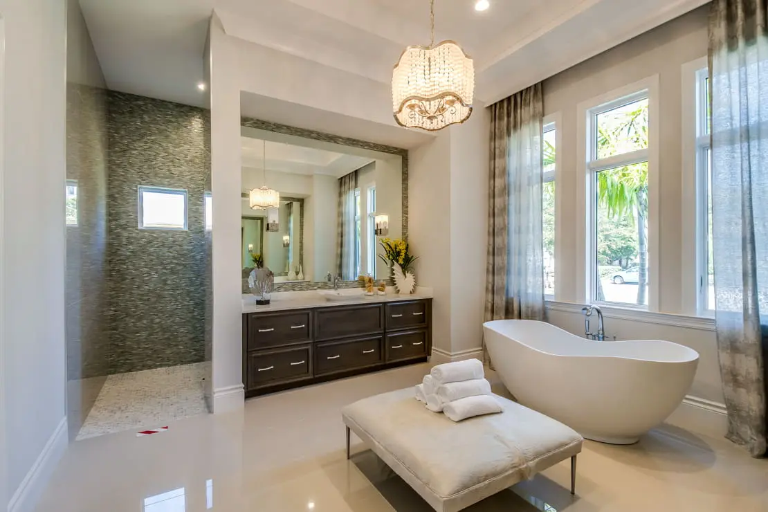 Luxe badkamer met een grote spiegel en natuurlijk lichtinval naast het bad